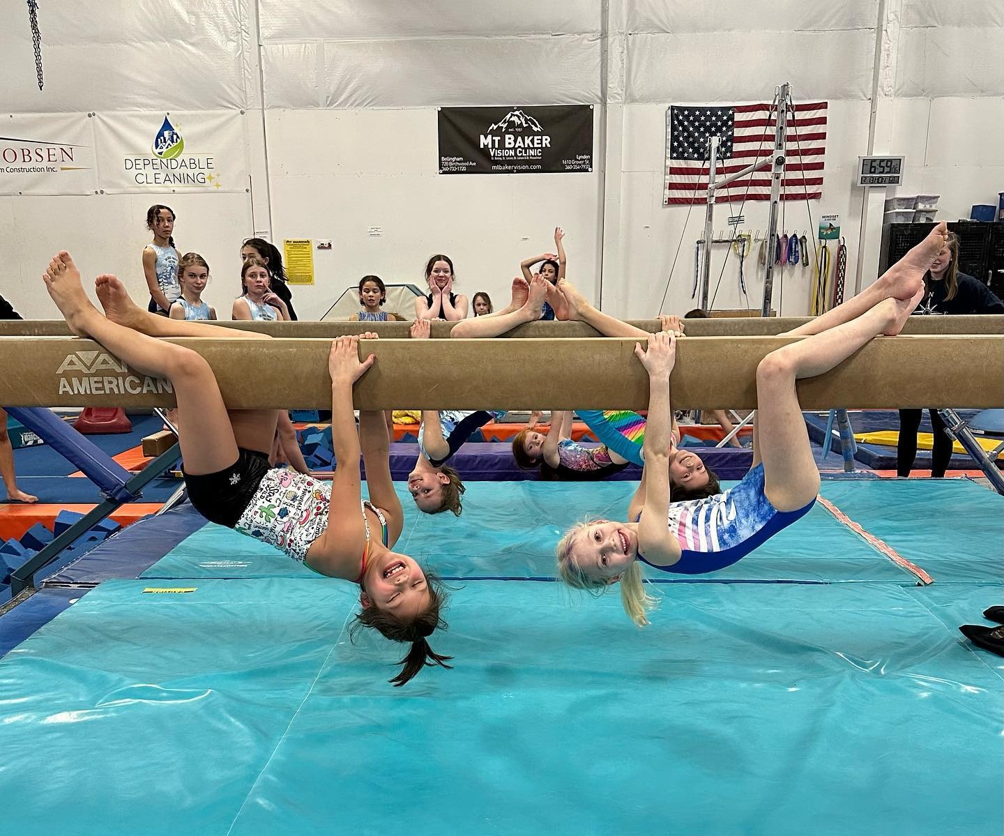 Gym Star gymnasts hanging from the balance beam