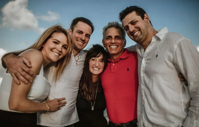Joe Strada with his wife and three grown sons outdoors on a bright day