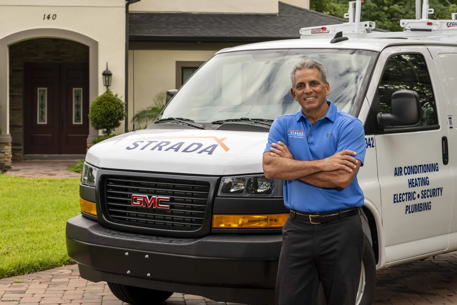 Joe Strada standing with arms crossed in front of a Strada service van